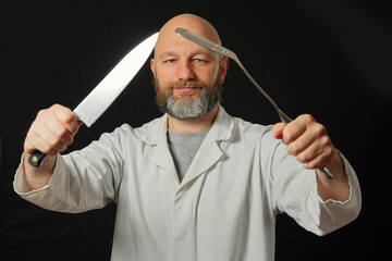 Bald male chef cook on a dark background. Man in his 40s with grey beard in white uniform. Holding kitchen utensils. Slim body type. Positive emotions on his face