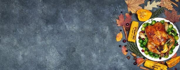 Thanksgiving turkey or chicken for a festive dinner. Food table banner background with autumn seasonal specialties for Thanksgiving Day. Fried chicken with pumpkin, vegetables and autumn decor on a