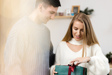 Sweet couple opening Christmas gifts in the living room at home