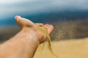 sand falls from the palm of your hand in the wind