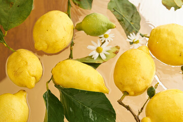Yellow ripe lemons with leaves in  water on beige background. Food photo pattern. Natural colors