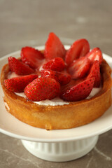 Stand with strawberry tart on gray textured table