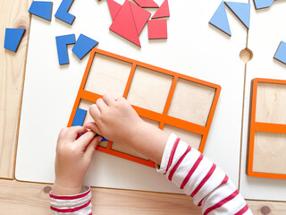 The child collects puzzles. Educational wooden toy for learning. Montessori materials. Fine motor skills, hand-eye coordination. Children's leisure, nursery.The concept of early development. squares. 