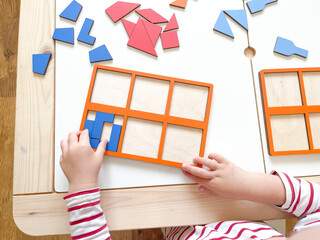 The child collects puzzles. Educational wooden toy for learning. Montessori materials. Fine motor skills, hand-eye coordination. Children's leisure, nursery.The concept of early development. squares. 