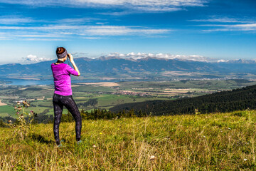 Hiker woman on top of the hill looking into to binoculars