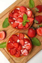 Cutting board with strawberry tarts on white background