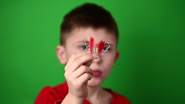 Plate for aligning teeth, a boy on a green background holding a plate, a dental plate in his hands.