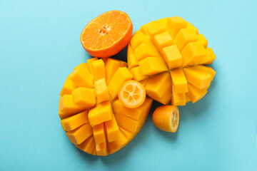 Ripe mango and orange on blue background