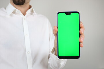 Elegant businessman holding vertically smartphone with green screen, chroma key 