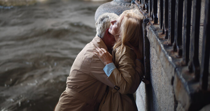 Passionate mature couple making out near city river