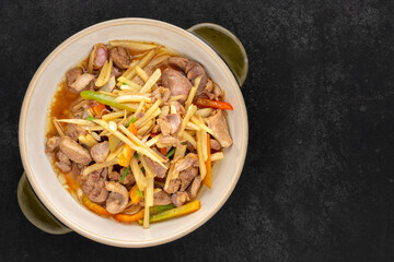 Kruang Nai Gai Pad King, Thai food, stir fried chicken offal, variety meats, pluck or organ meats with ginger in ceramic bowl on dark tone texture background, top view