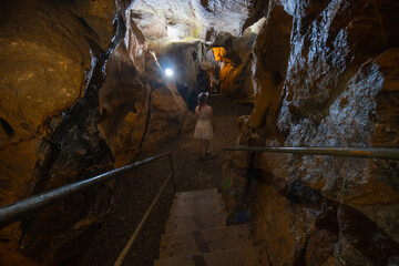 A girl in a white dress stands in a cave. Ancient formations of stone. Touristic hiking route. Concept of excursions and attractions. (Cüceler mağarası) Tırılar, Sapadere, Alanya