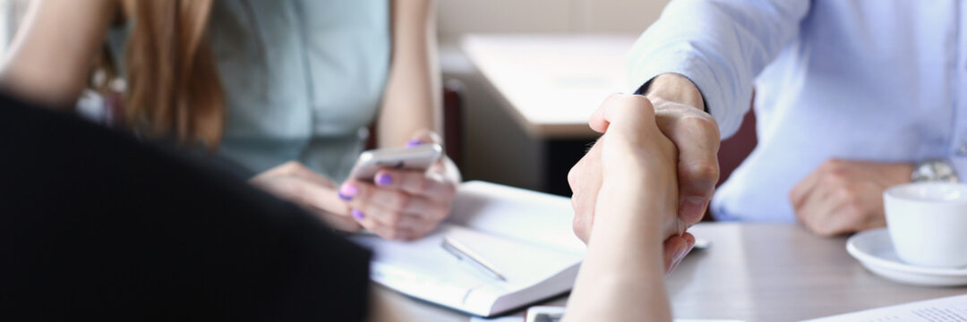 Smiling man and woman shake hands as hello in office