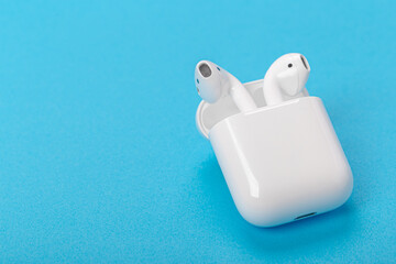 Modern wireless bluetooth headphones with charging case on a blue background. The concept of modern...