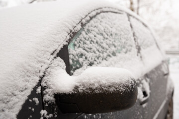 The beginning of spring. Unexpected snow covered cars and roads. Door mirror and glass of a car in the snow. Winter does not want to leave. Road safety. Selective focus