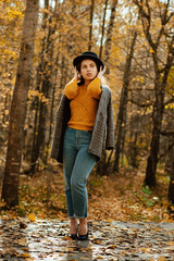 a young girl in a coat and hat walks through the autumn Park