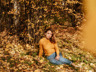 beautiful girl in autumn Park sitting on fallen leaves