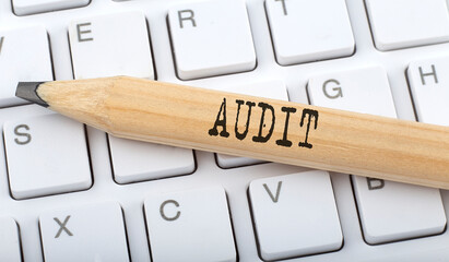 Text AUDIT on wooden pencil on white keyboard. Business concept