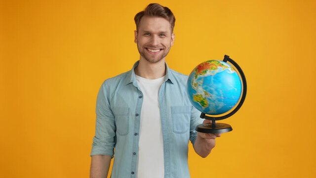 Positive funny guy spin globe sphere have fun study geography abroad tourism