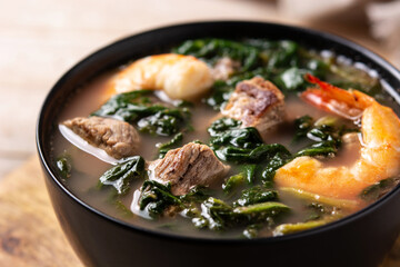 Beef, okra stew and spinach soup in bowl on wooden table. Close up