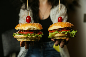 Woman hold two big beef burger sandwich and huge cheeseburger comparing. Fast food concept