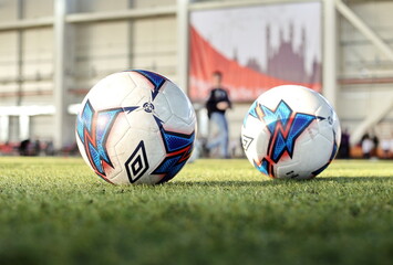 Two soccer balls on artificial grass on the stadium football field.