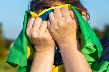 Desperate Brazilian woman covering her face with the national flag