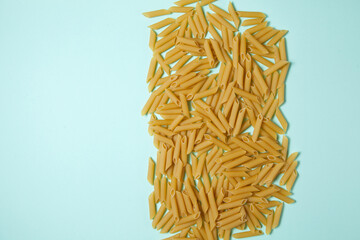 Penne pasta background. Pasta Penne texture background with space for text. Tube like macaroni. Heap of pasta.