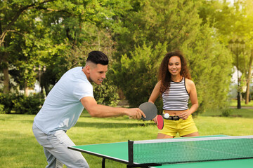 Friends playing ping pong outdoors on summer day