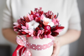 Dried flower bouquet with grasses in pink hat box in hands