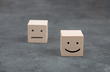 Wooden cubes with a happyand a sad face on a dark background, symbol