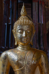 Fototapeta premium Beautiful ancient gilded Buddha statue with gold leaf inside heritage landmark Wat Phan Tao buddhist temple facade and gate, Chiang Mai, Thailand 