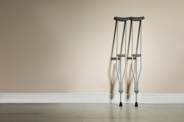 Pair of axillary crutches near color wall. Space for text