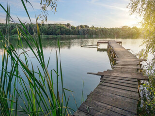 Fishing wooden pier on lake at sunset