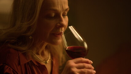Old woman drinking red wine glass at restaurant date. Upset retirement life