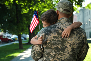 Soldier and his little son with flag of USA hugging outdoors - obrazy, fototapety, plakaty