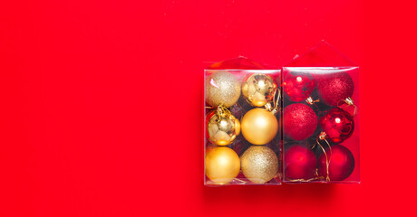 Red and golden Christmas tree balls toy are packed in a transparent plastic box. Preparing for the Christmas holiday market. Banner. Store selling new year decor. Post-holiday cleaning. Copy sapce