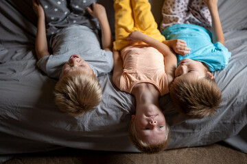 three funny boys are lying on the couch and playing. children are happy together