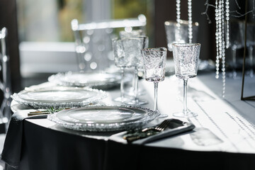 glass glasses and white plates. table setting in the interior of the restaurant. The decor of the festive table. In gray-silver tones with gold cutlery. Luxury wedding, party, birthday.