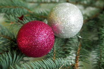 pink and gray shiny round Christmas toys lie on the branches of the Christmas tree. side view
