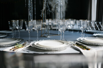 glass glasses and white plates. table setting in the interior of the restaurant. The decor of the festive table. In gray-silver tones with gold cutlery. Luxury wedding, party, birthday.