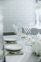 glass glasses and white plates. table setting in the interior of the restaurant. The decor of the festive table. In gray-silver tones with gold cutlery. Luxury wedding, party, birthday.