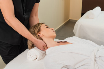 Obraz na płótnie Canvas Masseur doing neck massage to woman in bathrobe