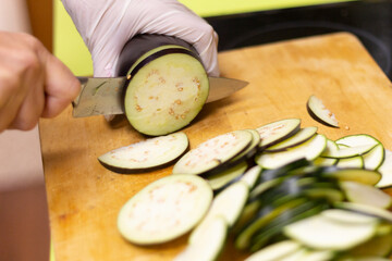 Cortando Berenjenas en rodajas  con cuchillo de cocina sobre tabla de cortar e madera 