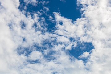 Fluffy white clouds framing the picture in the vibrant blue sky. View from below