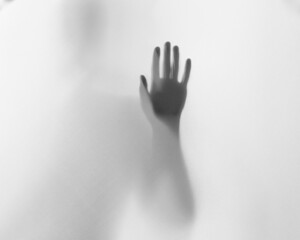 Halloween scary picture of hand silhouette behind the frosted glass