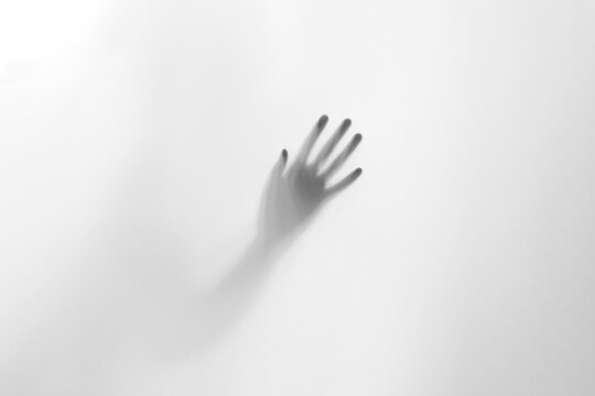 Halloween scary picture of hand silhouette behind the frosted glass