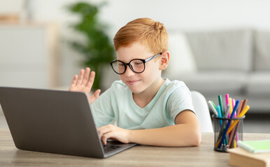 Cheerful redhead kid nerd having video call with tutor