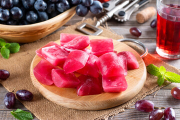Frozen wine cubes on a cutting board on a wooden table.