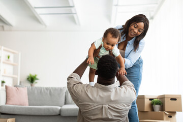 Happy African American family playing in new apartment